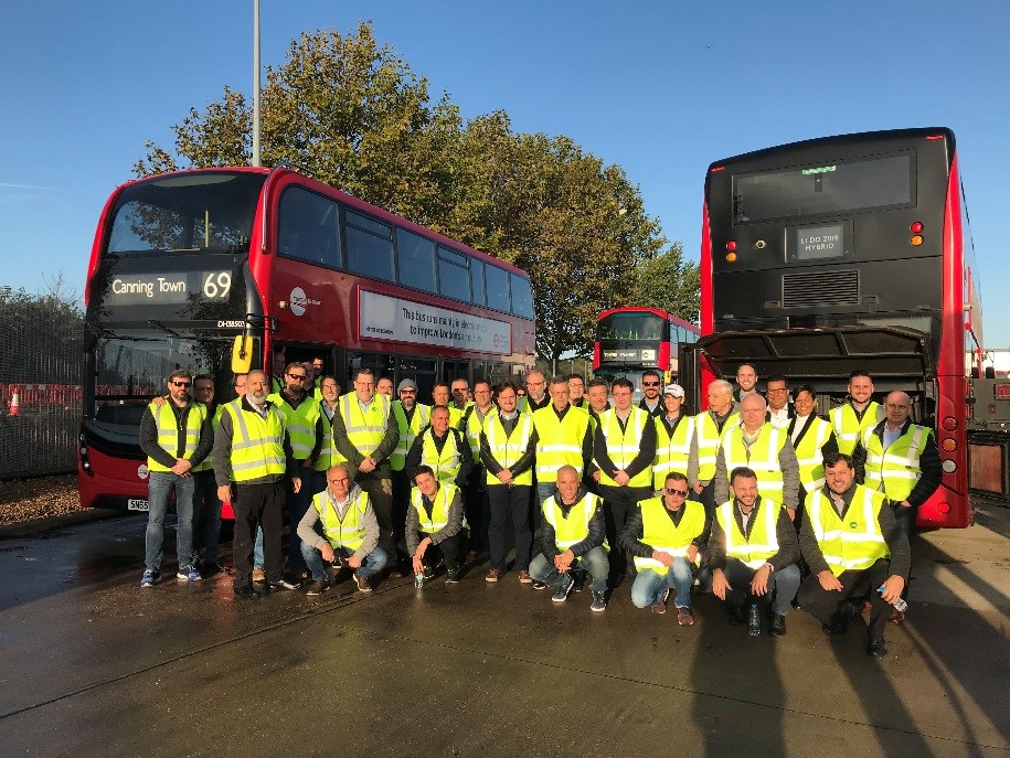 Group of people standing in front of two busses. 